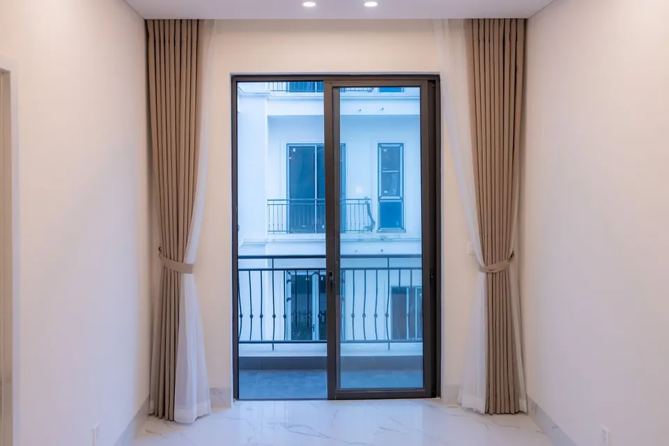 Puerta balconera de aluminio gris oscuro de dos hojas vista desde dentro de una habitación, con salida a un balcón